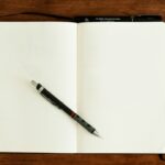 Notebook and pen on a desk used to track small completed goals